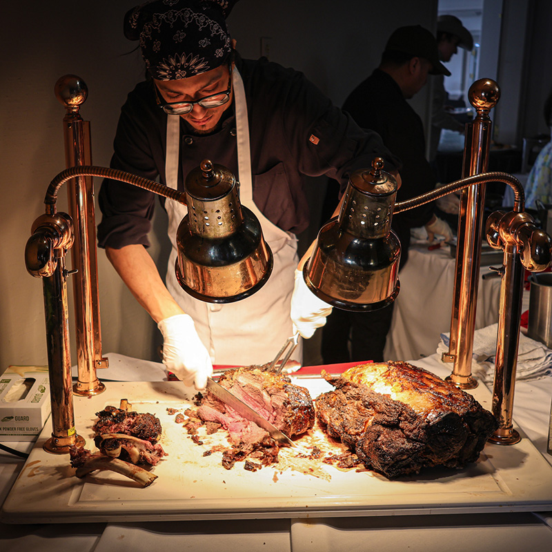 Server slicing meat at a buffet-style event.
